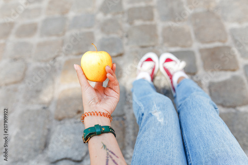 A woman tourist sits on a cobbles in the city and has an apple snack, travelers rest and diet concept photo