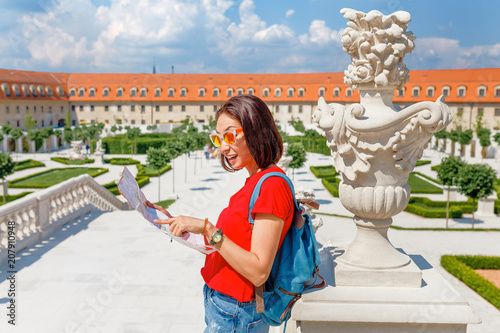 Sticker Happy young woman tourist reading map and admiring amazing view of a flower gard