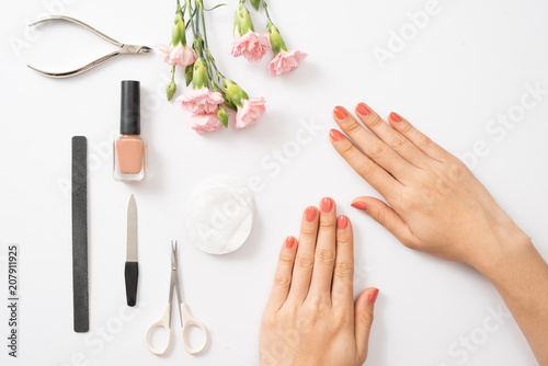 Female hands applying purple nail polish on wooden table with towel and nail set photo