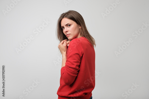 A young greedy woman hides something in her hands and looks warily forward.