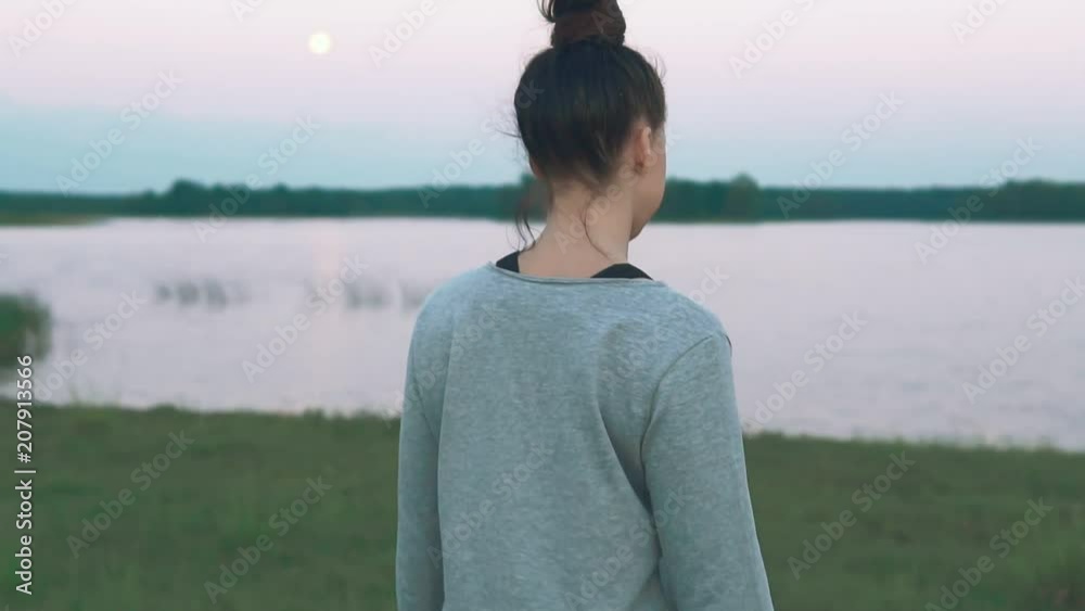 Young girl walking at coast in morning. Green grass, lake. Summer days. Slow motion. Healthy lifestyle concept Young girl walking at coast in morning. Green grass, lake. Summer days. Slow motion. Healthy lifestyle concept