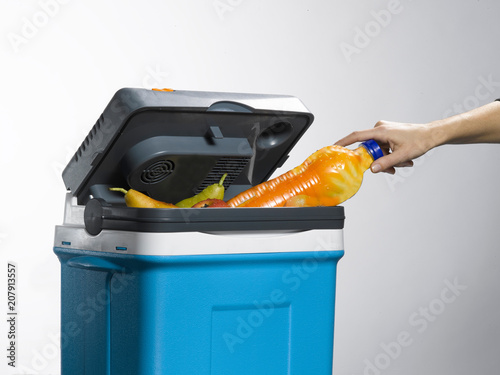 hand model pulling a soft drink bottle out of a cooler. isolated on white background. some fruit is visible from the inside of the portable fridge
