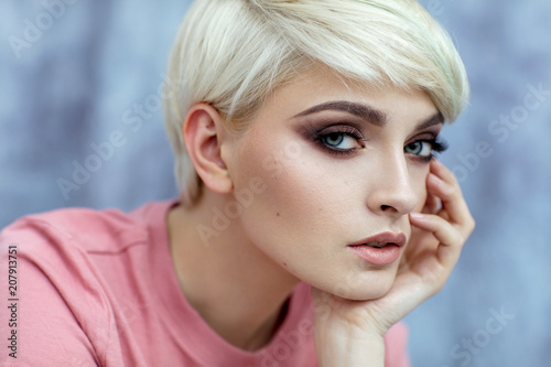 Portrait of young female model in fashionable make up with short hair looking at camera