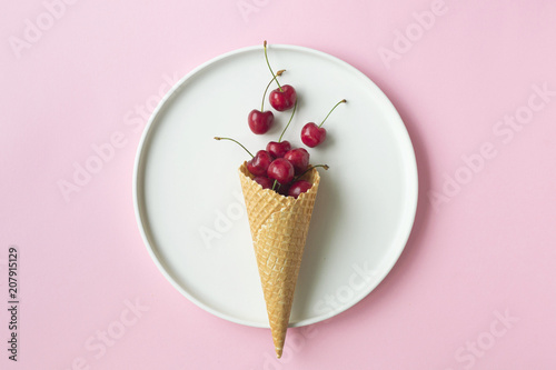 Spring or summer mood concept. Flat-lay of waffle sweet cone with berryy over pastel light pink background, top view. photo