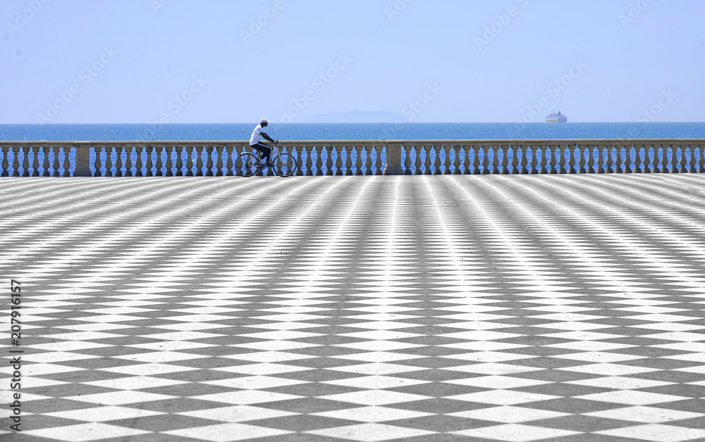 abstract patterns in open terrace Mascagni facing the sea in Livorno with man passing in bycicle, Italy