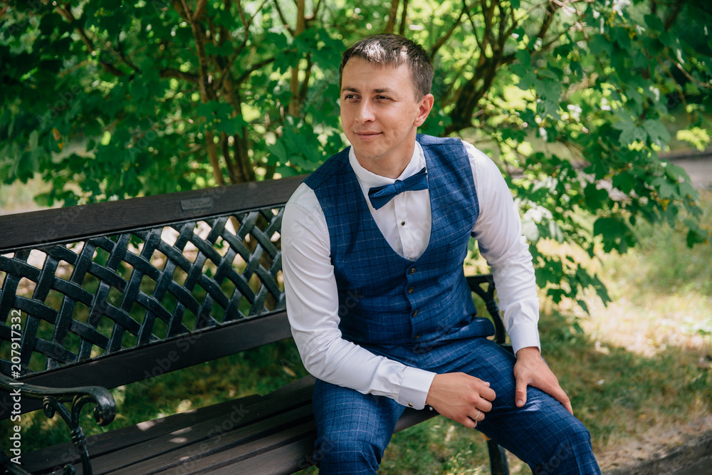A young guy in a stylish fashionable suit with a vest and a bow tie is