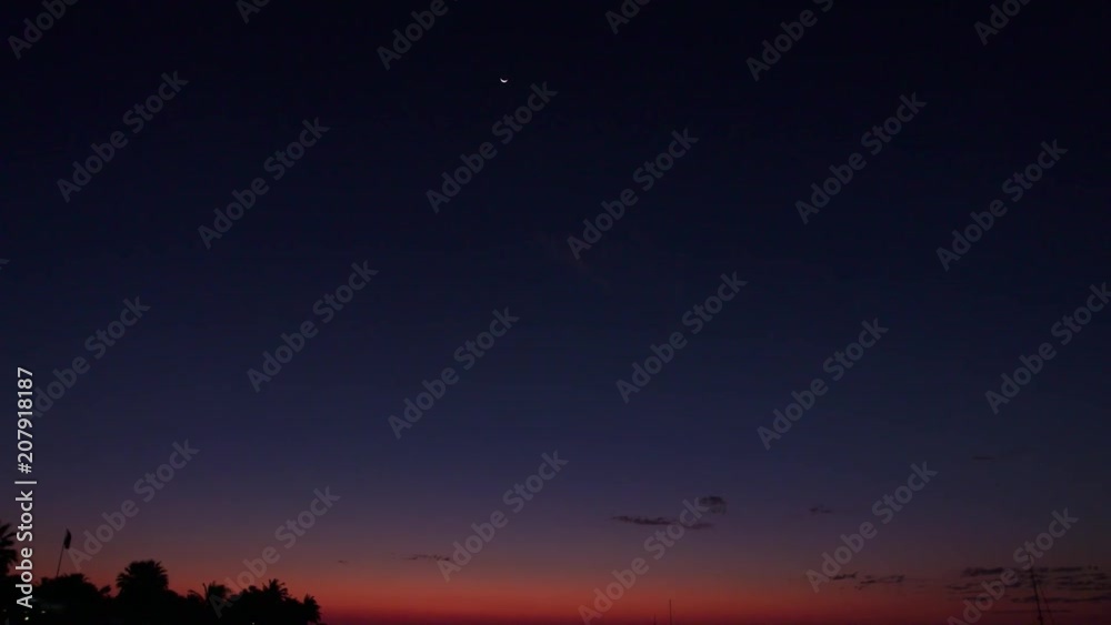 A wide shot of the ocean and horizon with boats and orange skies