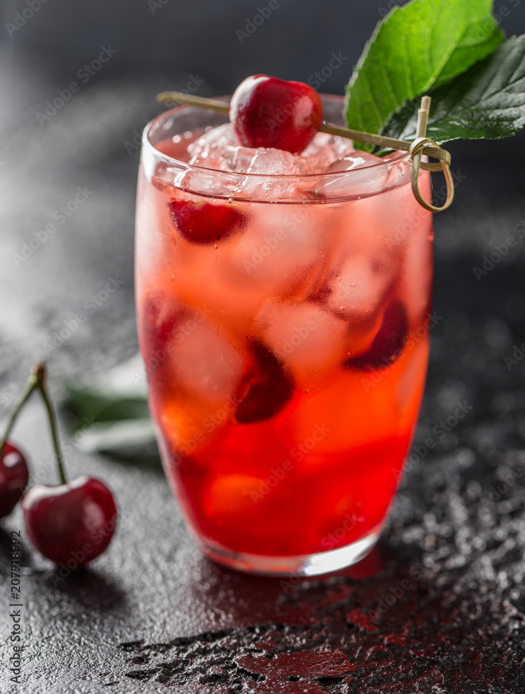 Fresh cherry cocktail. Fresh summer cocktail with cherry and ice cubes. Glass of cherry soda drink on dark stone background. Fresh cherry cocktail. Fresh summer cocktail with cherry and ice cubes. Glass of cherry soda drink on dark stone background.