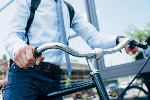 cropped shot of young businessman riding bicycle