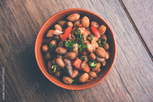 Boiled Peanut Chaat or Chatpata sing dana or shengdana or mungfali. served in a ceramic bowl over moody background photo