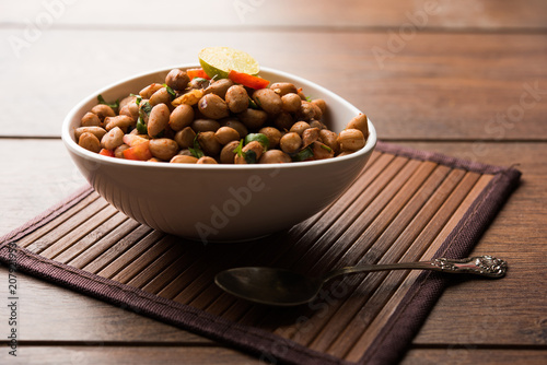 Boiled Peanut Chaat or Chatpata sing dana or shengdana or mungfali. served in a ceramic bowl over moody background