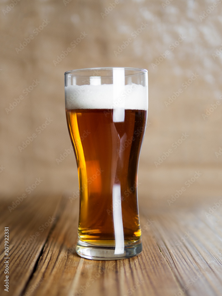 A glass of cold beer or ale on a wooden background