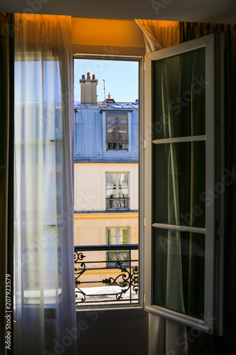 Window overlooking traditional french old house with typical balconies, rooftops and chimney pots.