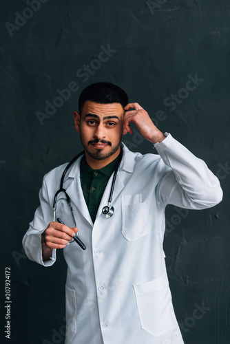 Portrait of confident young medical doctor on dark background. Young doctor man with stethoscope.doctor in a medical dressing gown