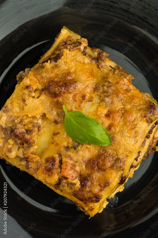 Traditional Lasagna With Minced Beef, Bolognese Sauce and Basil on Dark Plate. Italian Cuisine. Traditional Lasagna With Minced Beef, Bolognese Sauce and Basil on Dark Plate. Italian Cuisine.