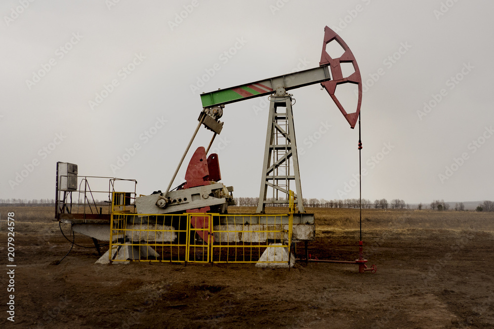 The beam pumping unit is homework, sunset in oil field. Oil pump oil rig energy industrial machine for petroleum. The pumping unit as the  pump installed on a well. Equipment of oil fields.
