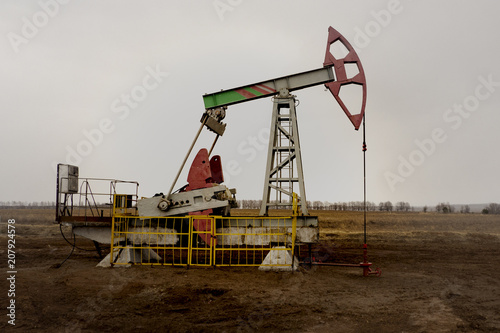 The beam pumping unit is homework, sunset in oil field. Oil pump oil rig energy industrial machine for petroleum. The pumping unit as the pump installed on a well. Equipment of oil fields.