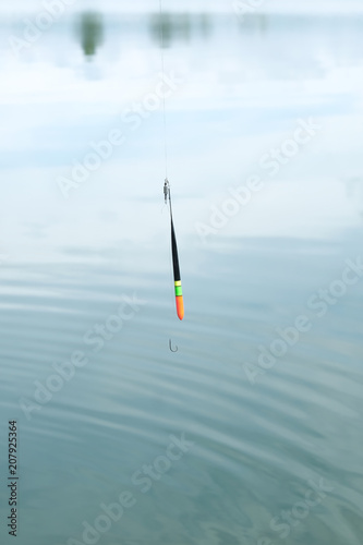 Fishing rod, fishing pole with a cork or float on the line on the lake background