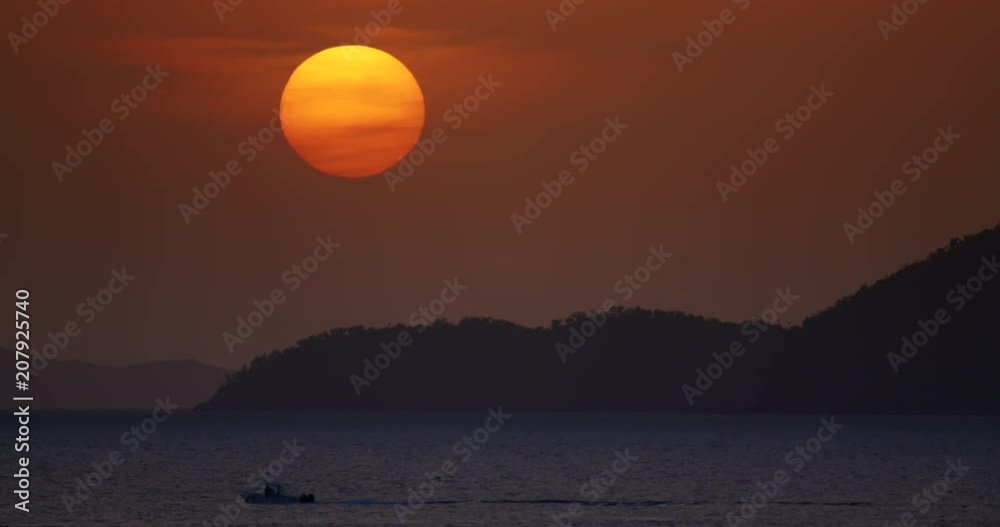 large sunset over tropical island with moving boat in the Caribbean large sunset over tropical island with moving boat in the Caribbean