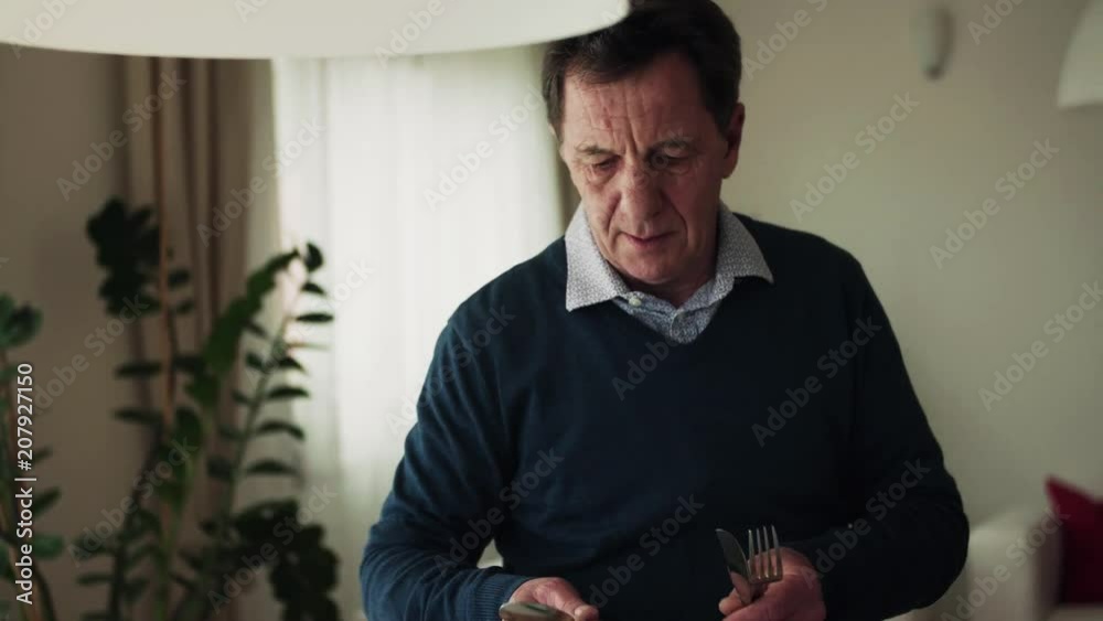 A senior man setting the table for dinner at home.