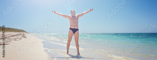 Happy man on beach. Rejoices to a victory success, hands up. Cuba, playa Ankon Trinidad Caribbean Sea. photo