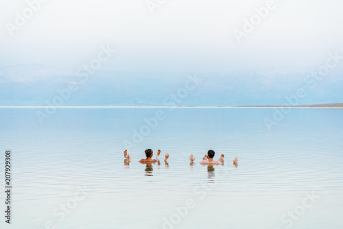 Young couple floating on surface of Dead Sea water and enjoying summer sun and vacation. Recreation tourism, healthy lifestyle, free time concept photo