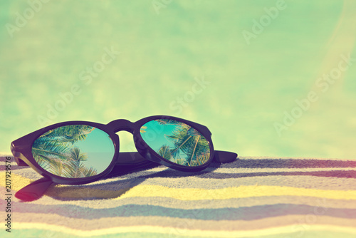 Fototapeta Naklejka Na Ścianę i Meble -  Sunglasses with palm trees reflections on a bath towel, vintage summer concept