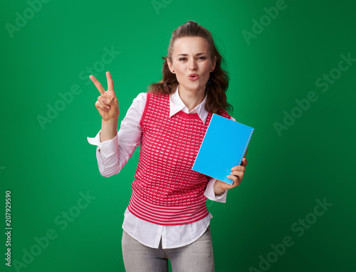 smiling young student woman with blue notebook showing victory