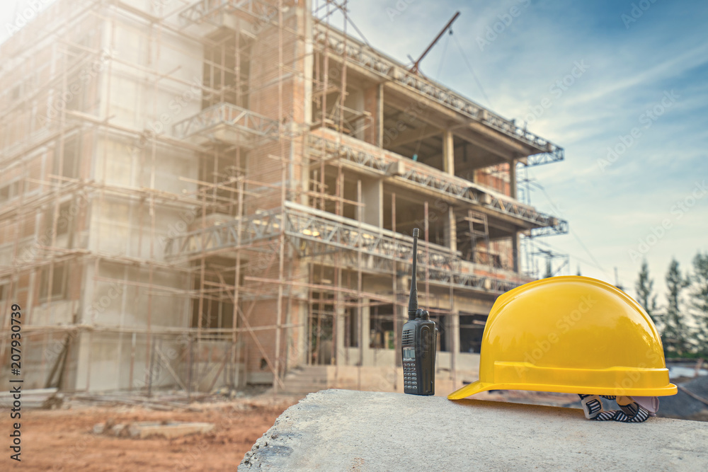 Construction concept with safety helmet and walkie talkie at construction site.
