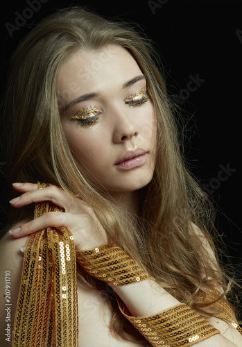 BLONDE GIRL WITH GOLD EYESHADOW AND CLOSED EYES ON BLACK BACKGOUND 
