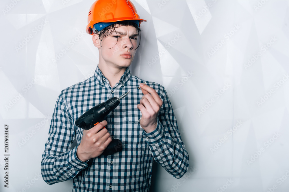 Dealing, real estate, engineer and industrial concept.Portrait of a builder in an orange helmet. Man with drill.Male car mechanic with drill on white background Dealing, real estate, engineer and industrial concept.Portrait of a builder in an orange helmet. Man with drill.Male car mechanic with drill on white background