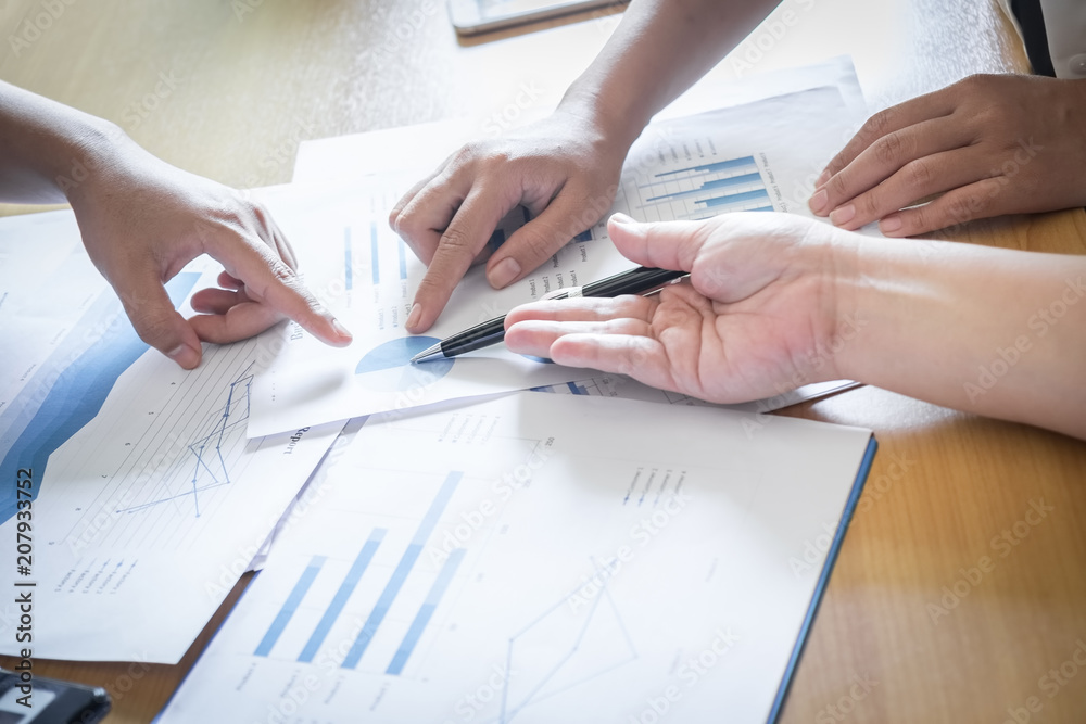 Female hands pointing at turnover graph while discussing it on wooden desk in office. group support concept. Female hands pointing at turnover graph while discussing it on wooden desk in office. group support concept.