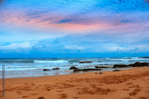 desierta playa de arena con rocas   acompa  ada de un bonito  con nubes en el atardecer