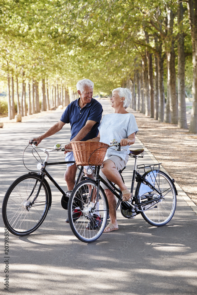 Smiling Senior Couple Cycling On Country Road Smiling Senior Couple Cycling On Country Road