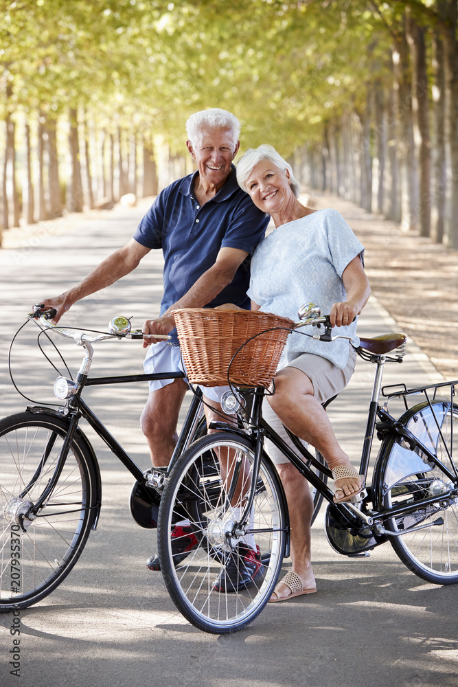 Portrait Of Smiling Senior Couple Cycling On Country Road Portrait Of Smiling Senior Couple Cycling On Country Road