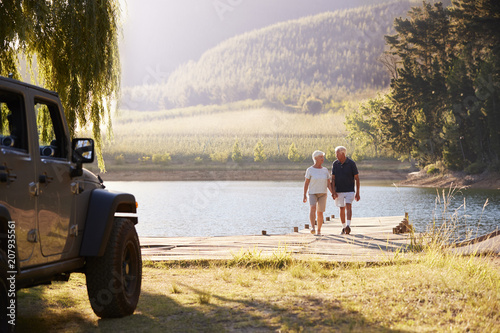 Senior Couple Walking By Lake At The End Of Road Trip