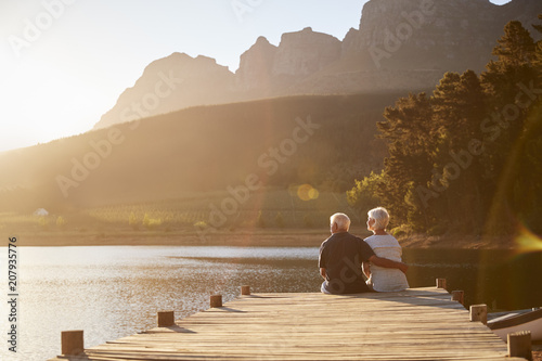 Romantic Senior Couple Sitting On Wooden Jetty By Lake photo