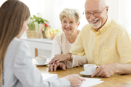 Happy senior man and his wife conversing with financial advisor about loan