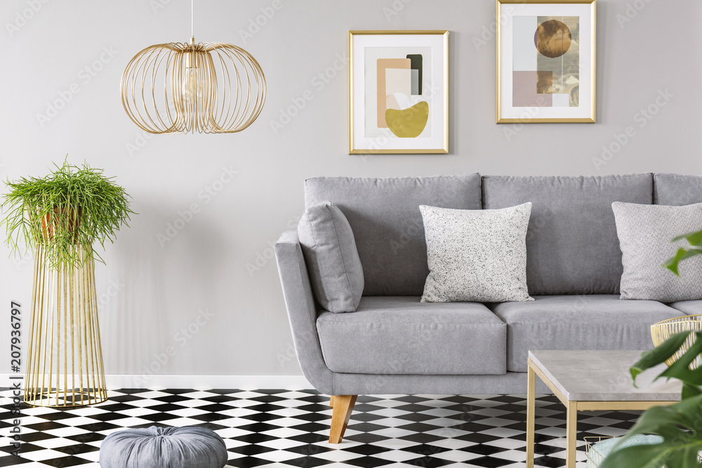 Real photo of a living room interior with gold posters on the walls, grey sofa with cushions and checkered floor - obrazy, fototapety, plakaty 