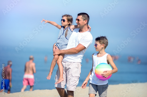 Father with children playing football on the beach at the day time. 