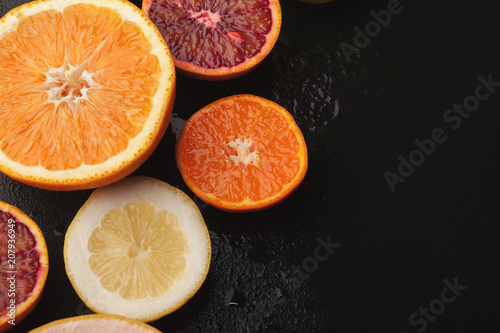 Heap of citruses and juice glass on black background