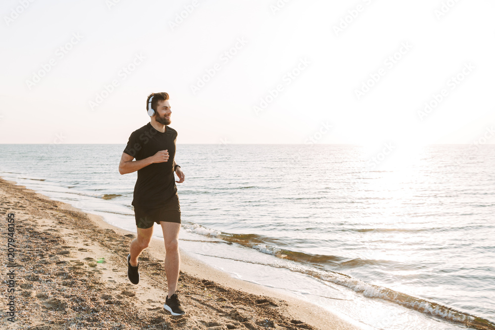 Happy young sportsman running at the beach