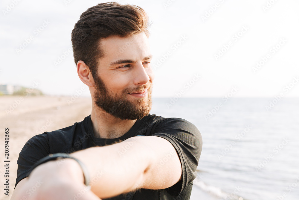 Smiling young sportsman doing stretching exercises Smiling young sportsman doing stretching exercises