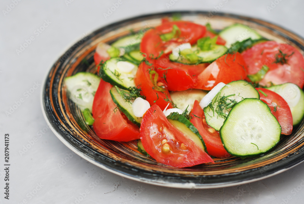 Tomato and cucumber salad with black pepper vegan food with fork gray textured cement background
