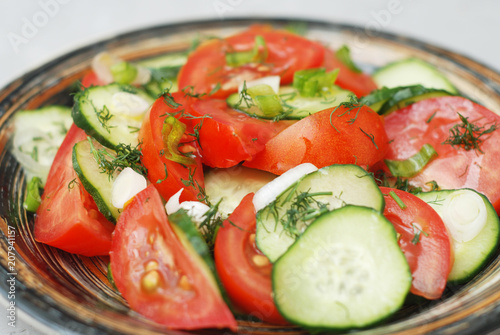 Tomato and cucumber salad vegan food with fork gray textured cement background