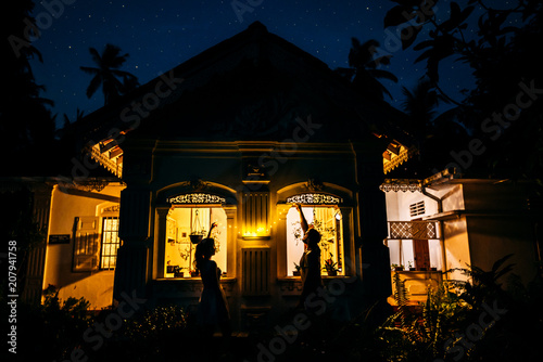 A couple in love adorns the house with a garland. Boy and girl decorate the house. The guy and the girl is preparing for the holiday. Christmas in Asia. New year in the tropics.