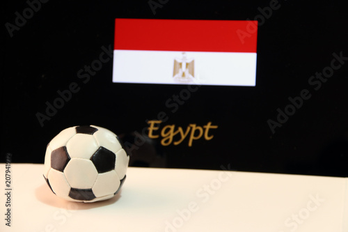 Small football on the white floor and Egyptian nation flag with the text of Egypt background. The concept of sport.