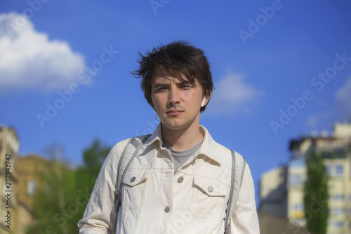 Young man wearing white denim jacket open air walk.