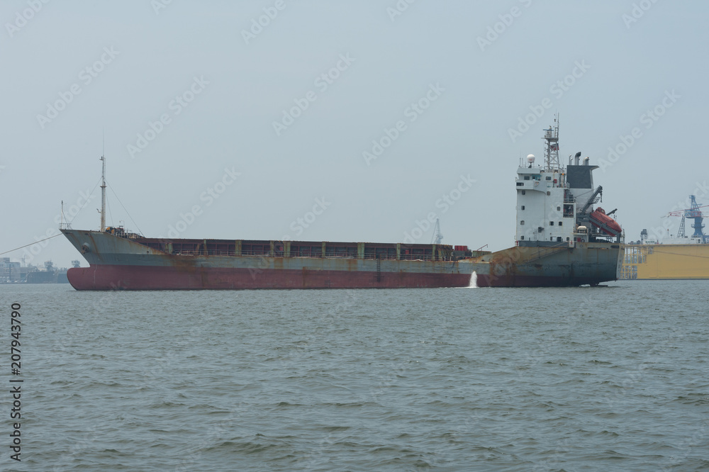 KAOHSIUNG, TAIWAN - CIRCA June, 2018:A large cargo ship moves towards the exit of Kaohsiung harbor