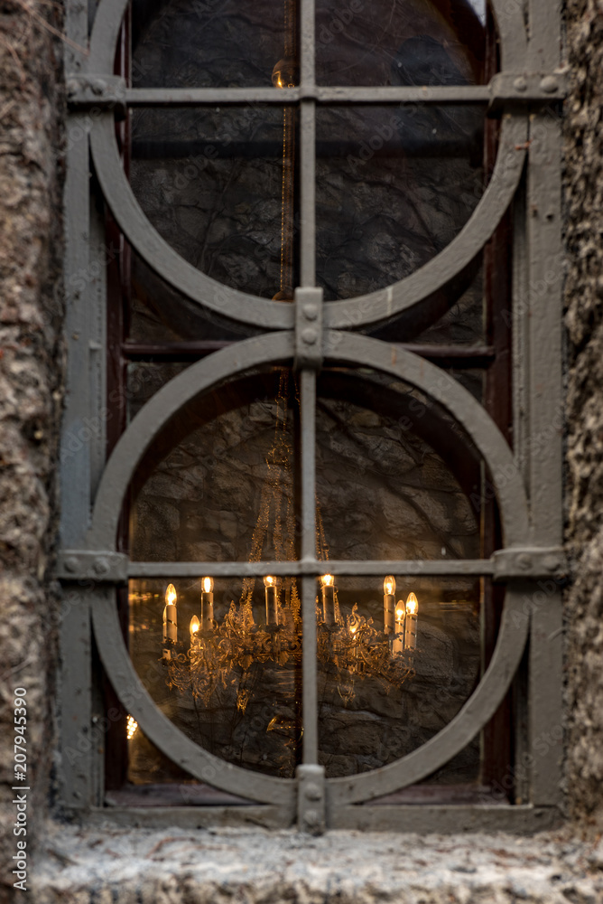 Old and aged, historic church window with stone frame and grids. Beautiful church chandelier. Light and hope concept. Old and aged, historic church window with stone frame and grids. Beautiful church chandelier. Light and hope concept.